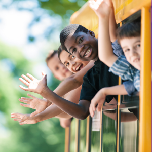  4 children waving out of school bus windows